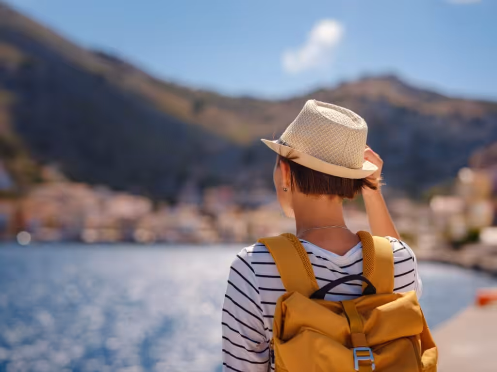 A traveler in a sun hat looking out over a coastal town, illustrating Signs of Professional Burnout in The Woodlands and psychological flexibility.