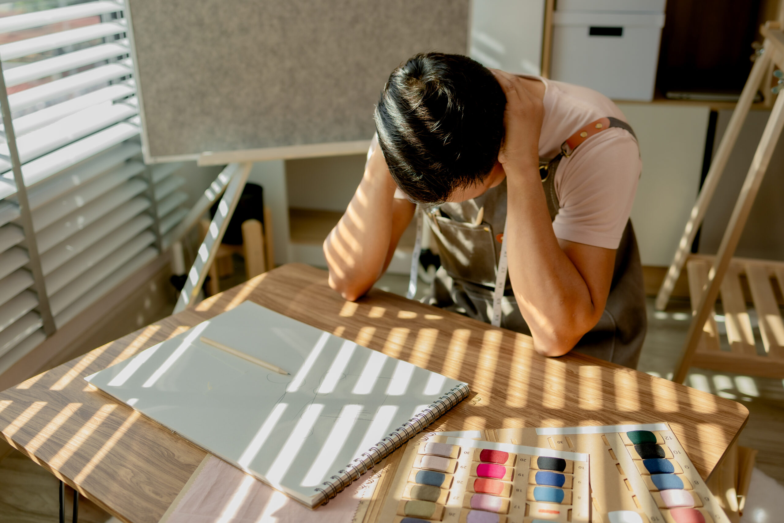 A stressed professional leaning over a desk illustrating how high achievers in The Woodlands often mask the symptoms of adult ADHD and depression  Acceptance Path Counseling
