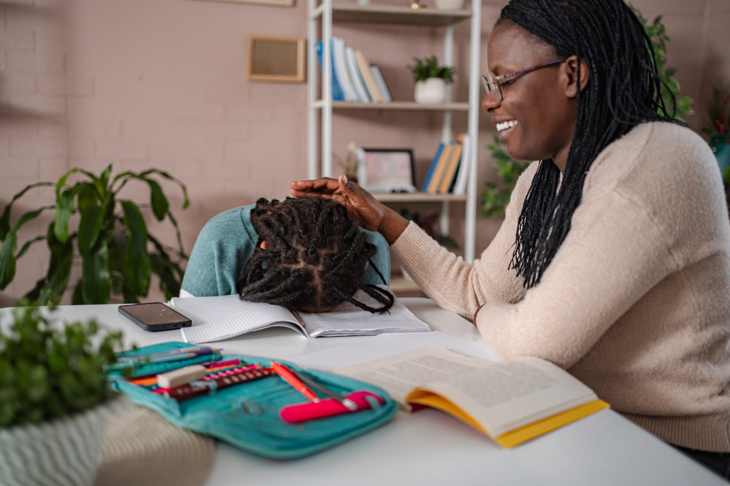 Mother comforting tired daughter doing schoolwork at home Acceptance Path Counseling A supportive environment demonstrating ADHD coping strategies featuring a child focused on a sensory task while a caregiver provides calm patient presence to assist with daily executive functioning challenges