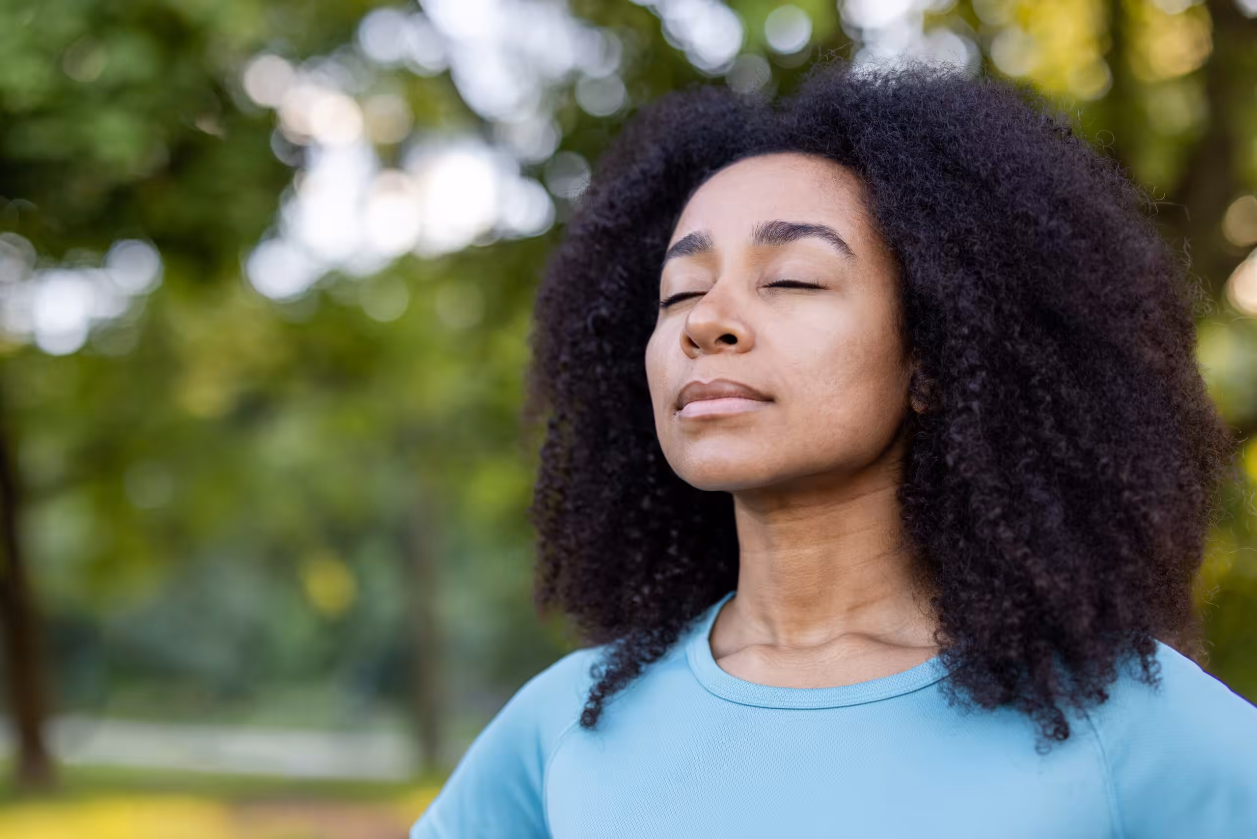 A woman practicing mindfulness meditation outdoors in a park representing practical exercises for mental clarity and Breaking Intrusive Thought Loops in The Woodlands