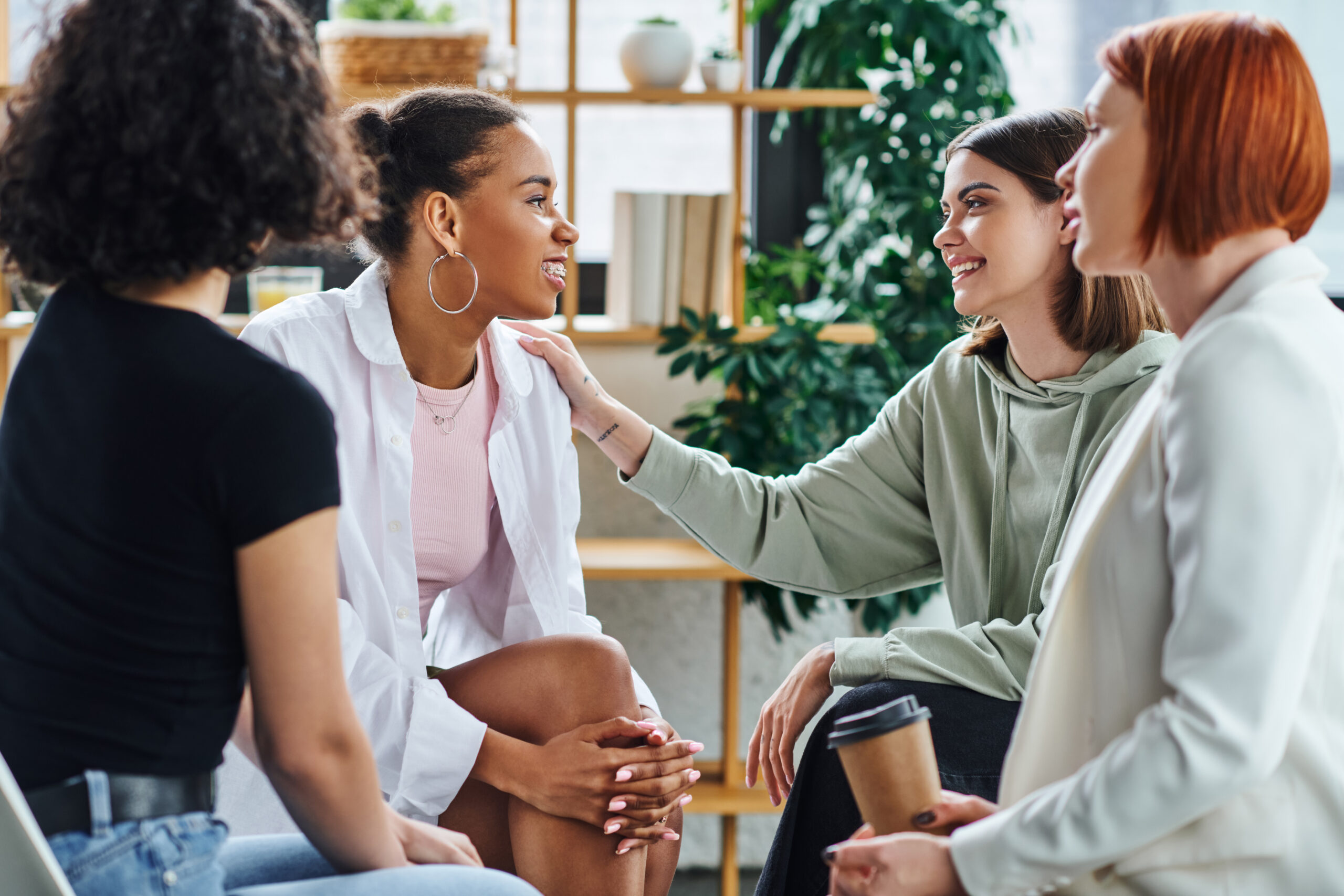 A small group of women sitting closely together in a circle sharing stories and offering empathetic listening during a community group for depression support