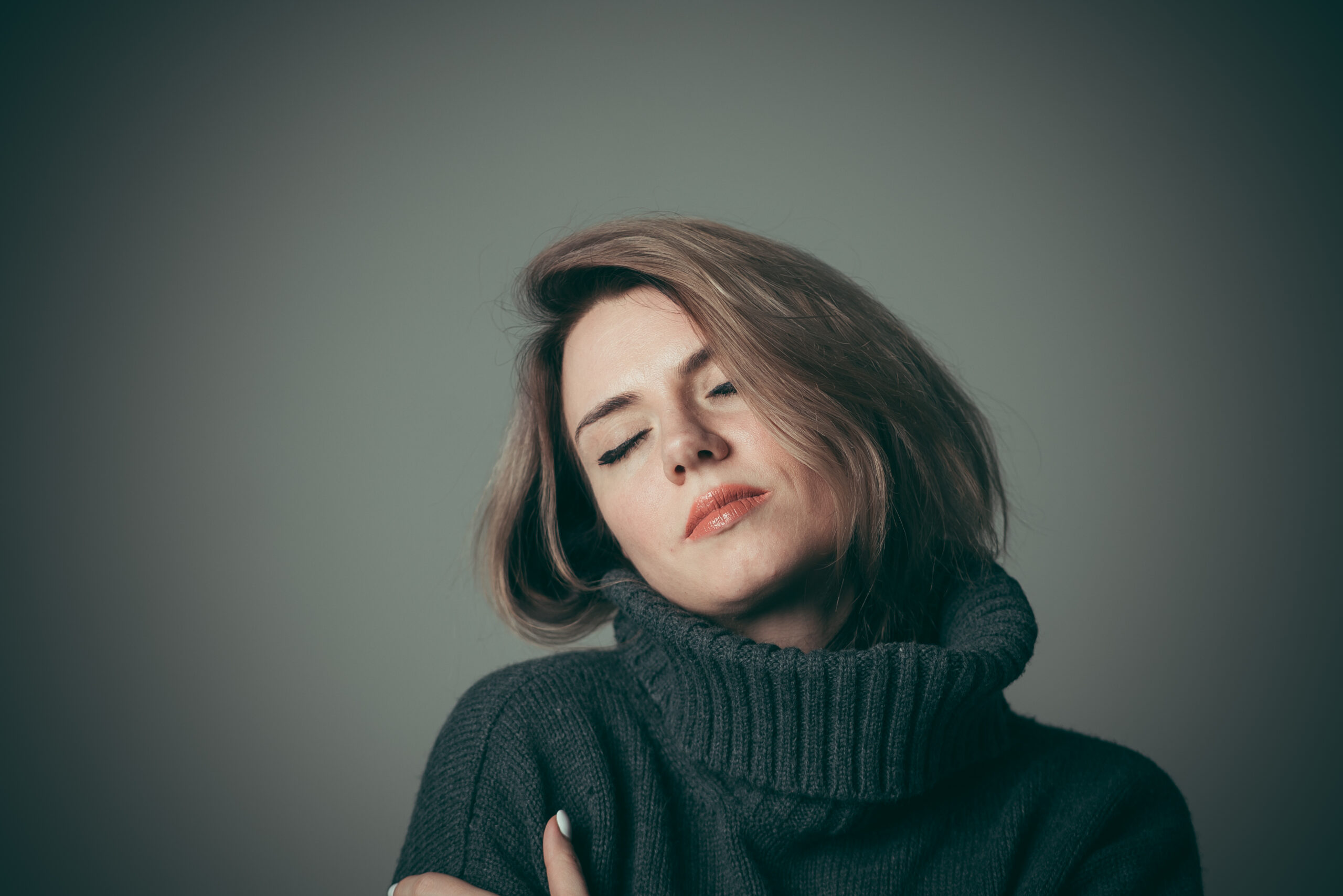 A woman in Kohrville with eyes closed and arms wrapped around herself  carrying the private weight of moral scrupulosity OCD when faith becomes a source of relentless guilt rather than peace addressed at Acceptance Path Counseling
