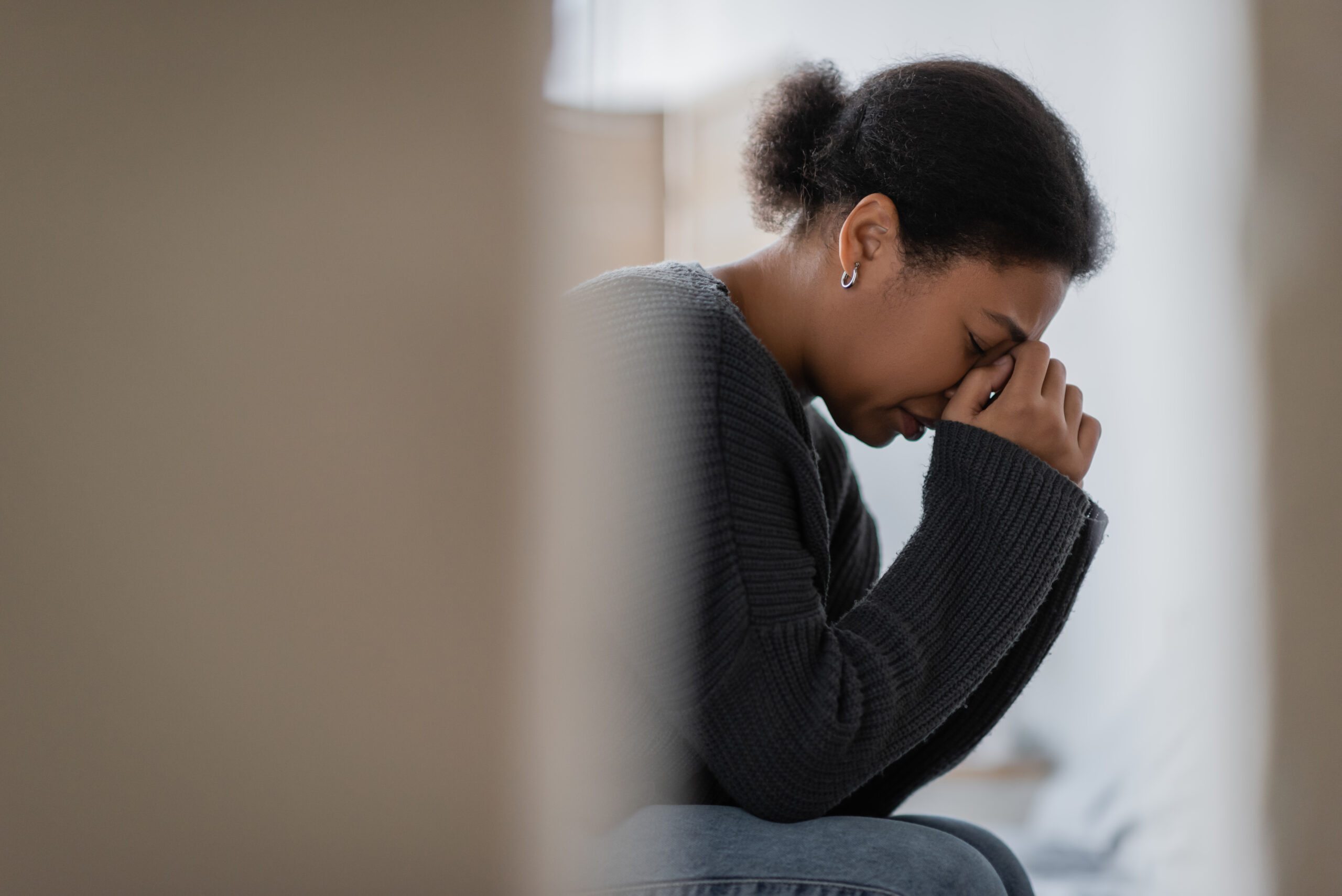 A blurred woman sits with her head in her hands showing deep focus or distress at a desk The visual illustrates executive dysfunction intense mental overwhelm and the cognitive strategies involved in how to cope with depression