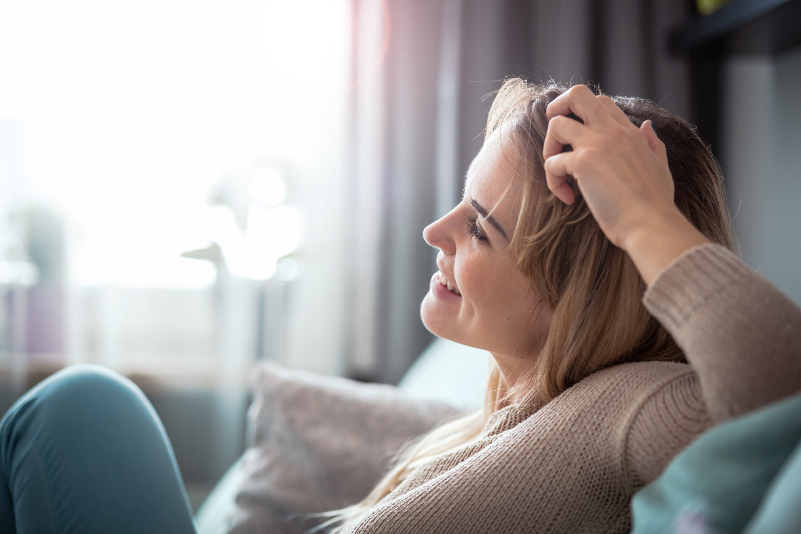 A relaxed woman smiles peacefully while resting her hand on her head in a brightly lit room in The Woodlands The image highlights long term emotional recovery and successful positive coping mechanisms for depression