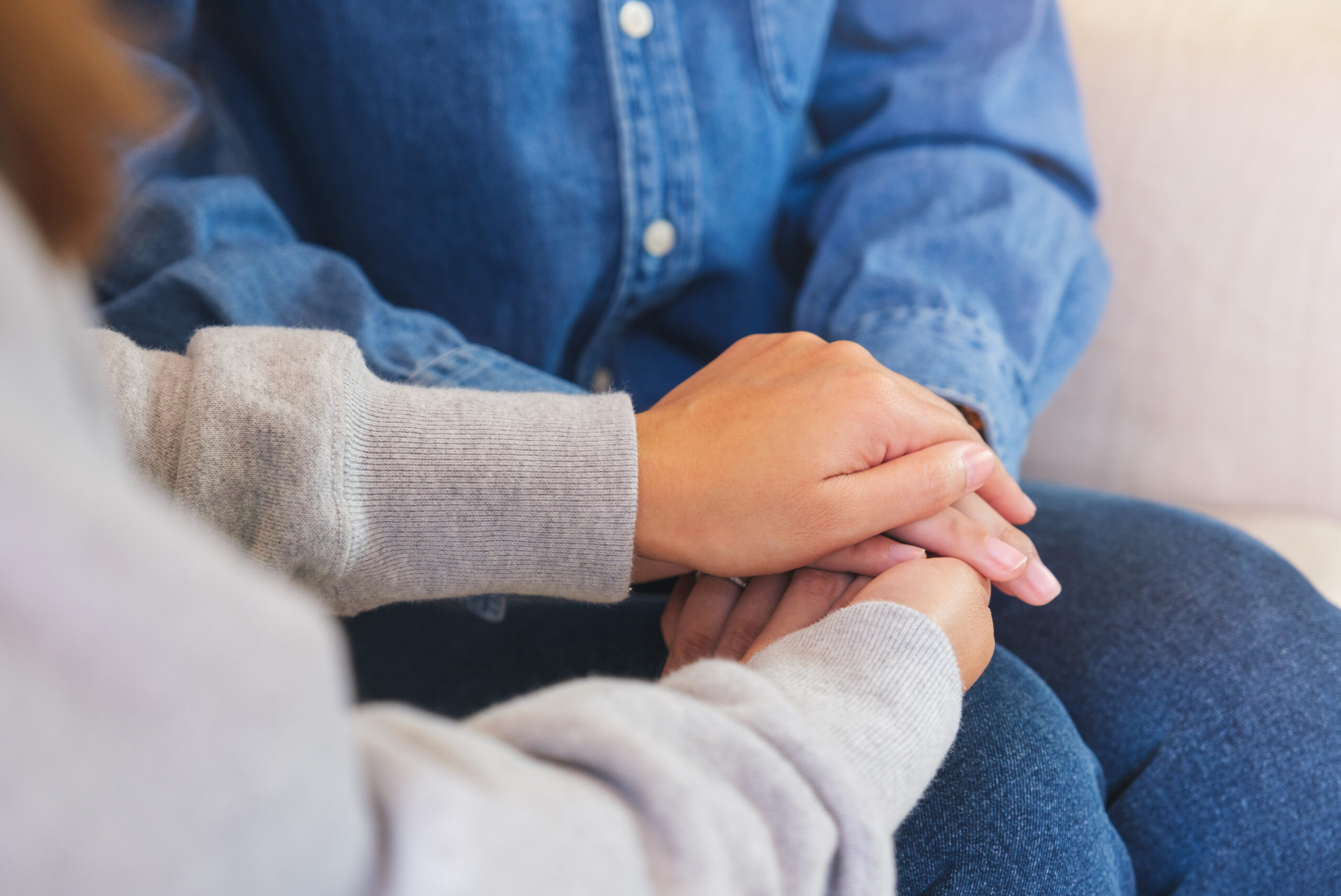 A close up view of one person gently placing their hand over another's hand, capturing a simple yet profound gesture of interpersonal depression support.