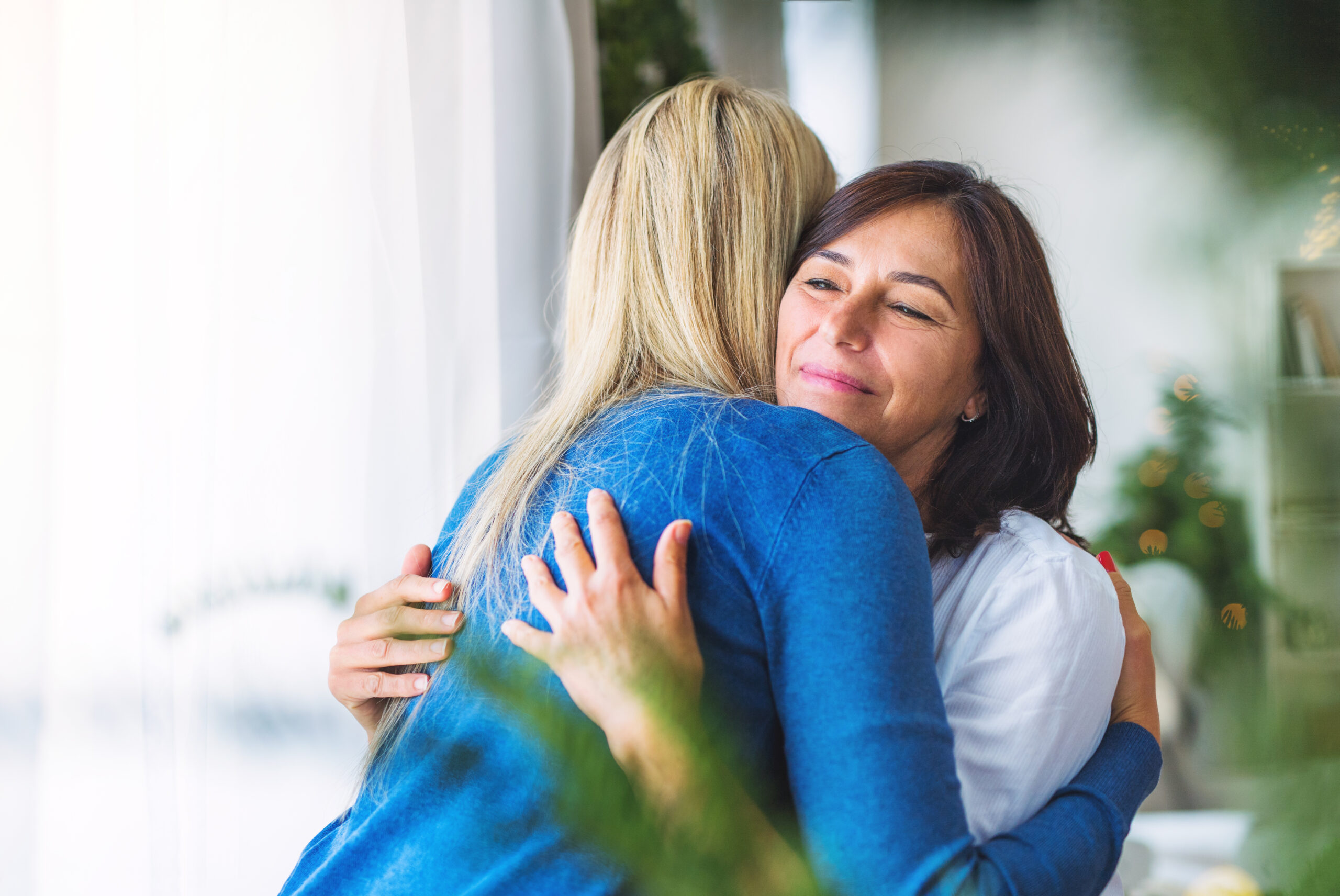 Two close friends sharing a warm reassuring embrace indoors showing emotional connection and how to support someone with depression by making them feel loved