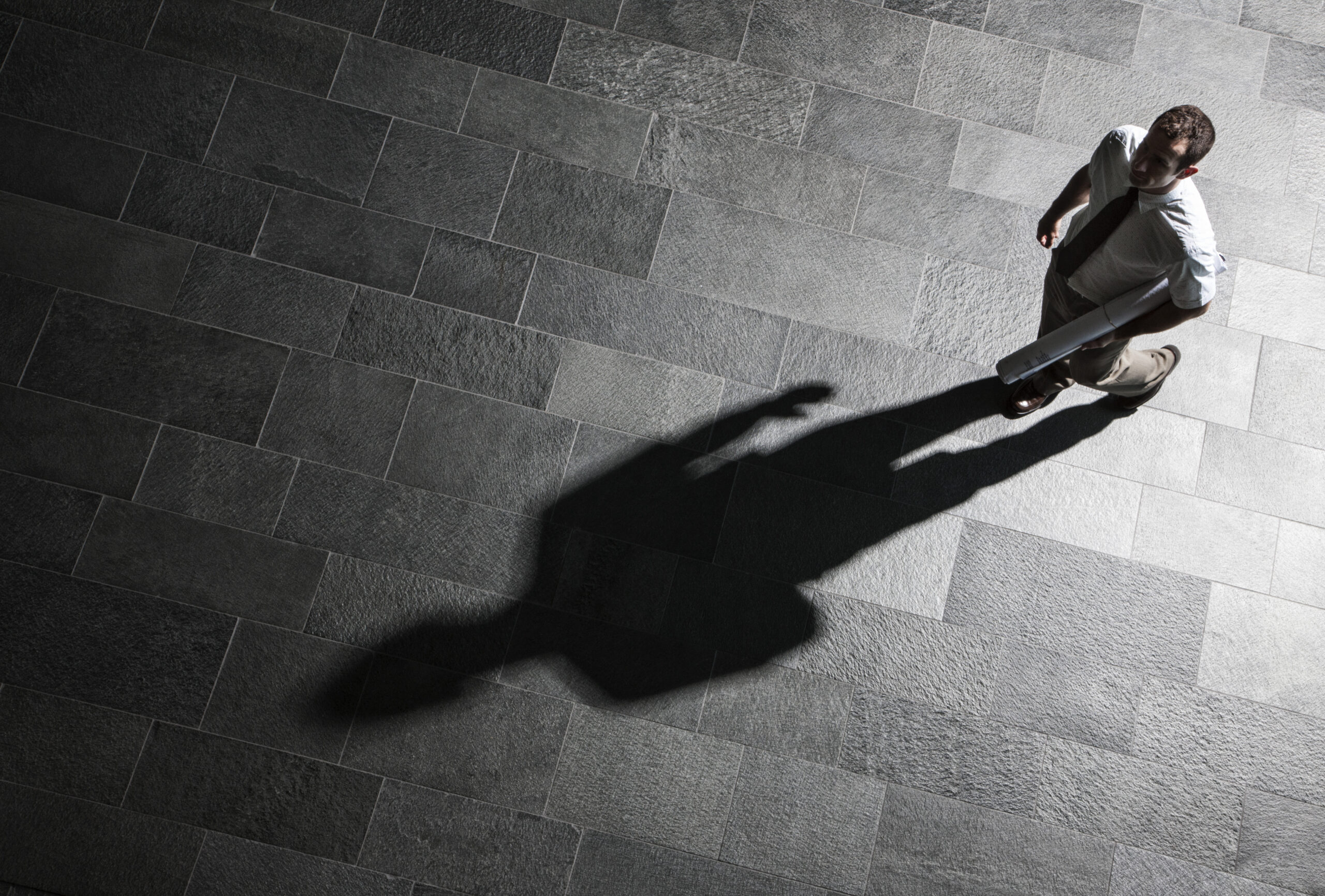 A professional in Greenwood Forest casting a long dark shadow across stone tiles  a visual metaphor for the gap between who someone with harm OCD examples actually is and what the intrusive thoughts make them fear they could be explored at Acceptance Path Counseling