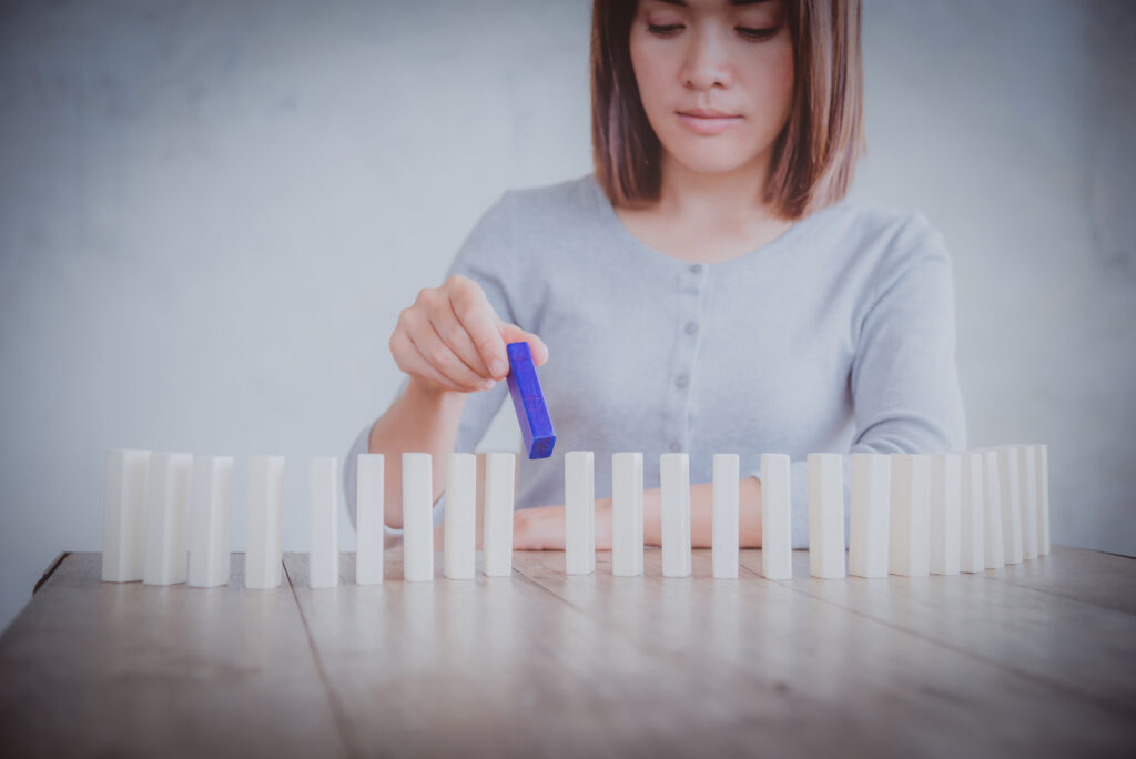 A person uses a small tool to meticulously line up a row of white blocks on a table. This structured action visualizes the need for symmetry when dealing with adhd and ocd together.