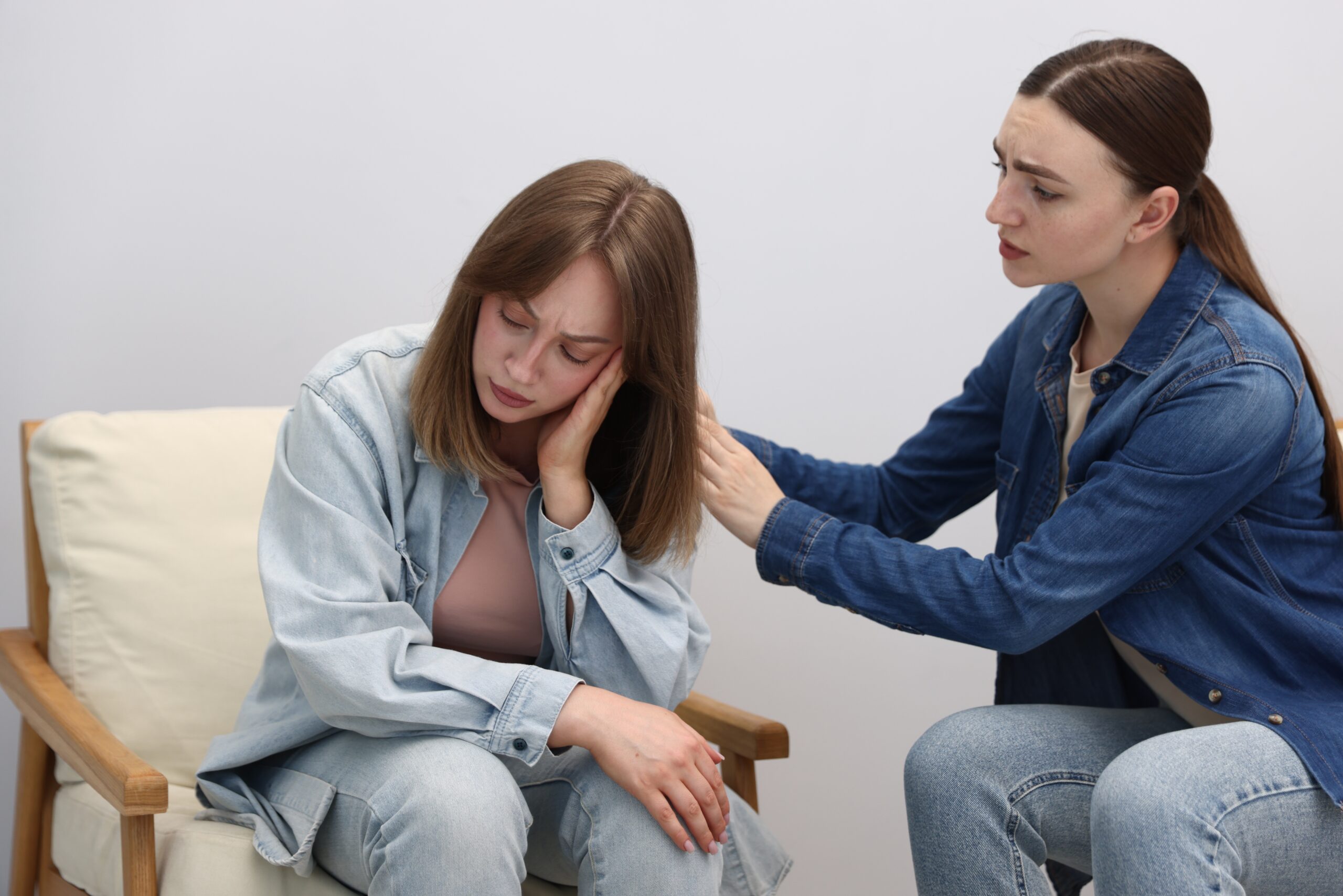 Woman apologizing to her offended friend on armchair near grey wall at home Acceptance Path Counseling Emotional support and understanding for someone with disordered eating patterns