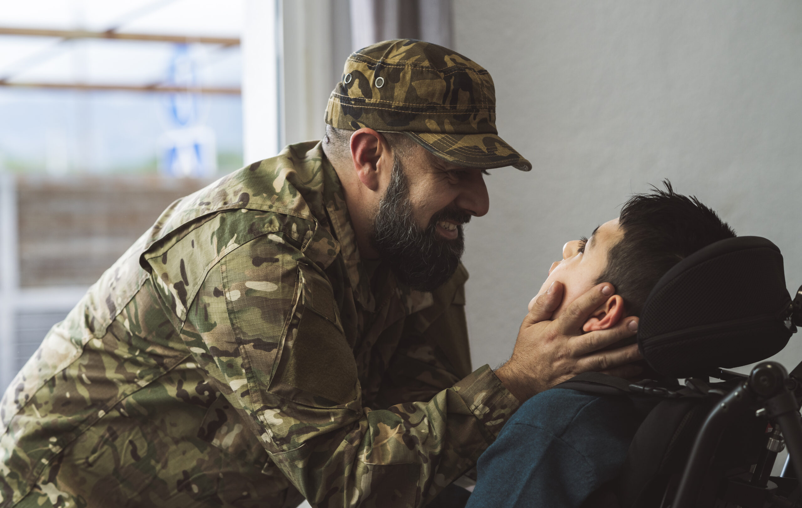 Hispanic veteran soldier caresses disabled son in a wheelchair when returning from military service to home Unconditional love and inclusion concept Focus on father face Acceptance Path Counseling Individual practicing grounding techniques to manage PTSD triggers in daily life