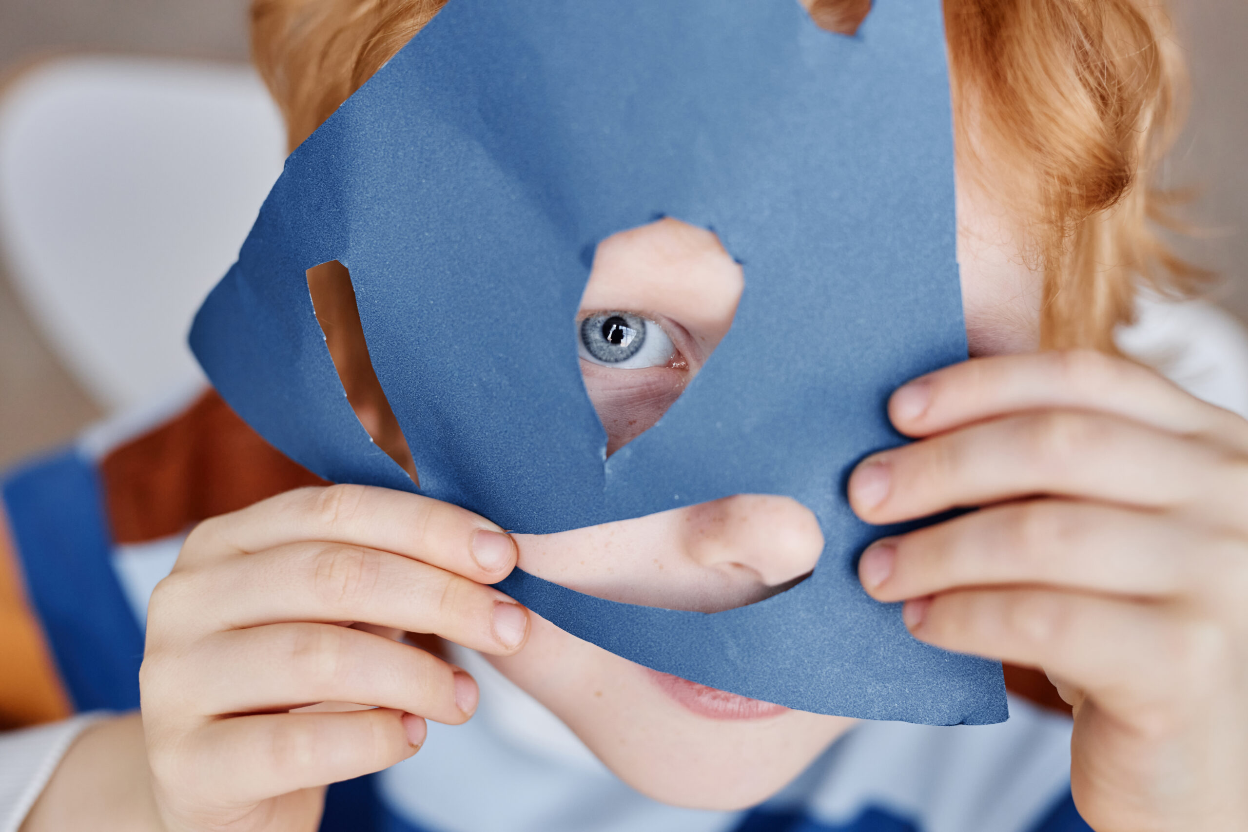 Closeup of cute blueeyed little boy covering face with blue paper mask Acceptance Path Counseling Adult using detailed reminders and rehearsed routines to conceal difficulties associated with ADHD masking