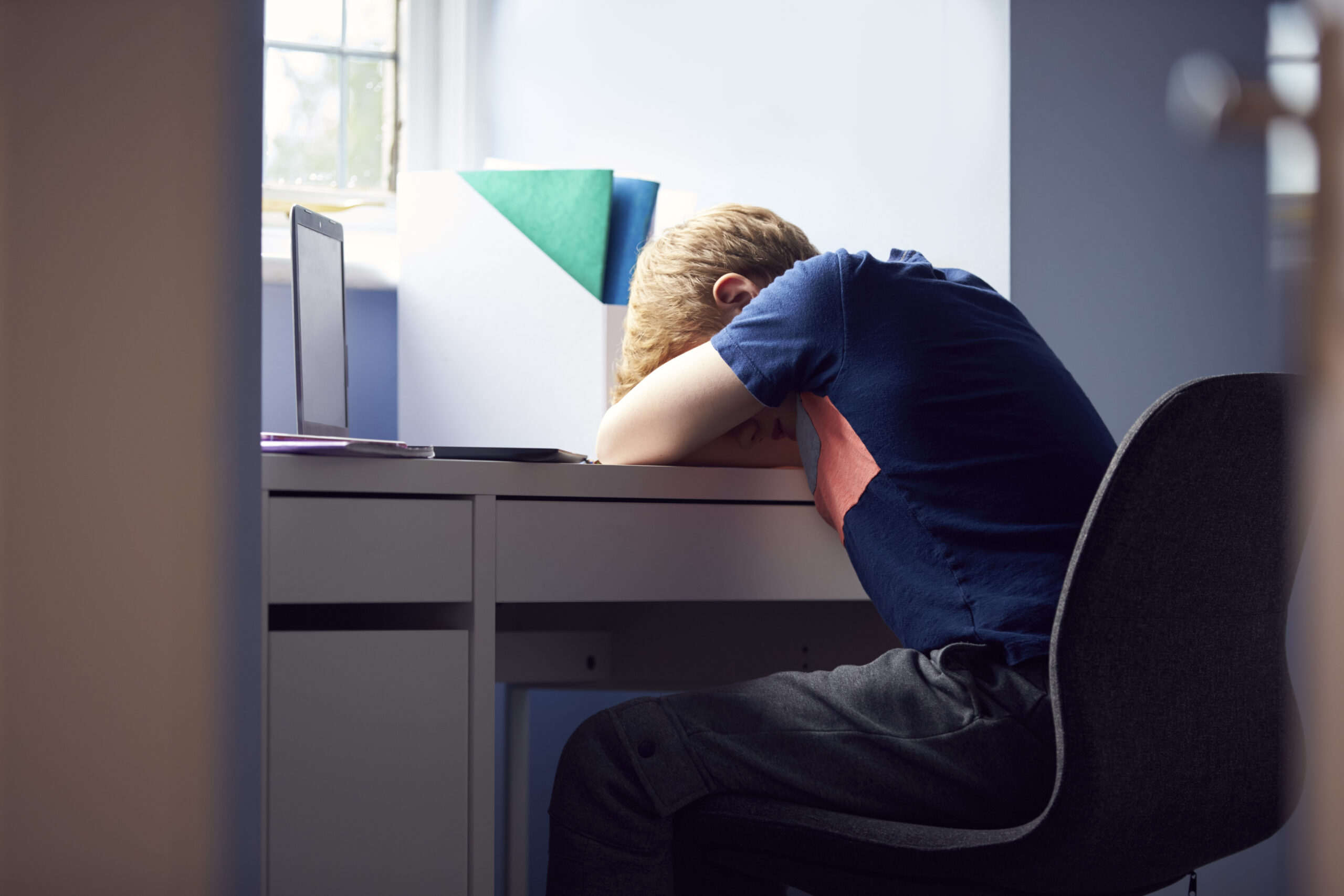 Stressed Boy Sitting With Head On Desk HomeSchooling With Laptop During Health Pandemic Acceptance Path Counseling Individual using a planner while managing low energy executive dysfunction ADHD and depression