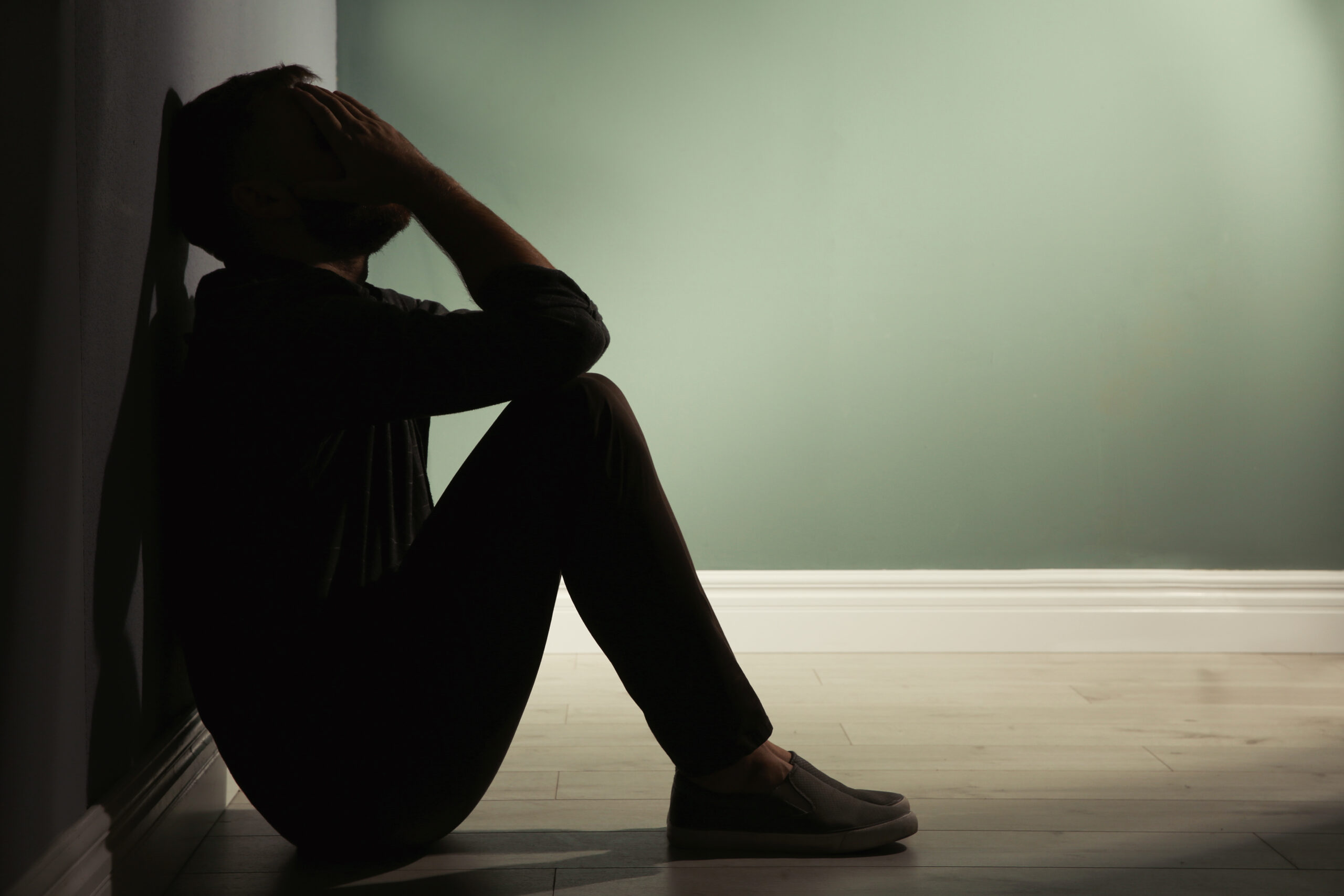 Depressed young man sitting on floor in darkness Acceptance Path Counseling Counseling session exploring the relationship between ADHD depression shame and emotional exhaustion
