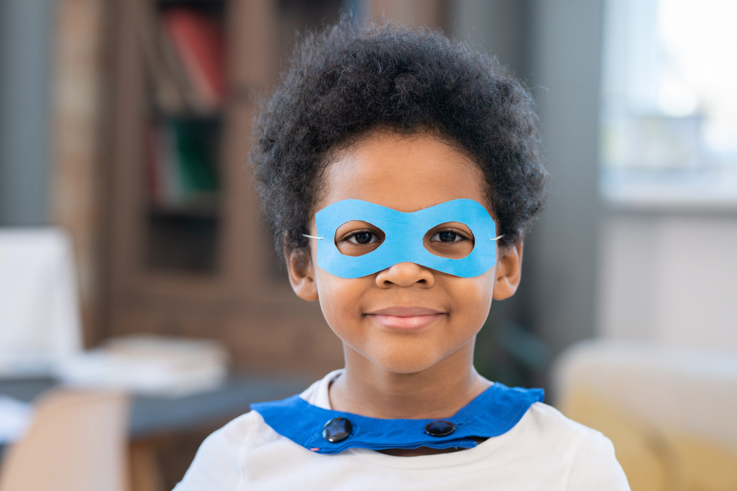 Cute boy in costume of superhero looking at you through blue paper eyeglasses Acceptance Path Counseling Person suppressing restlessness and monitoring their behavior as part of ADHD masking