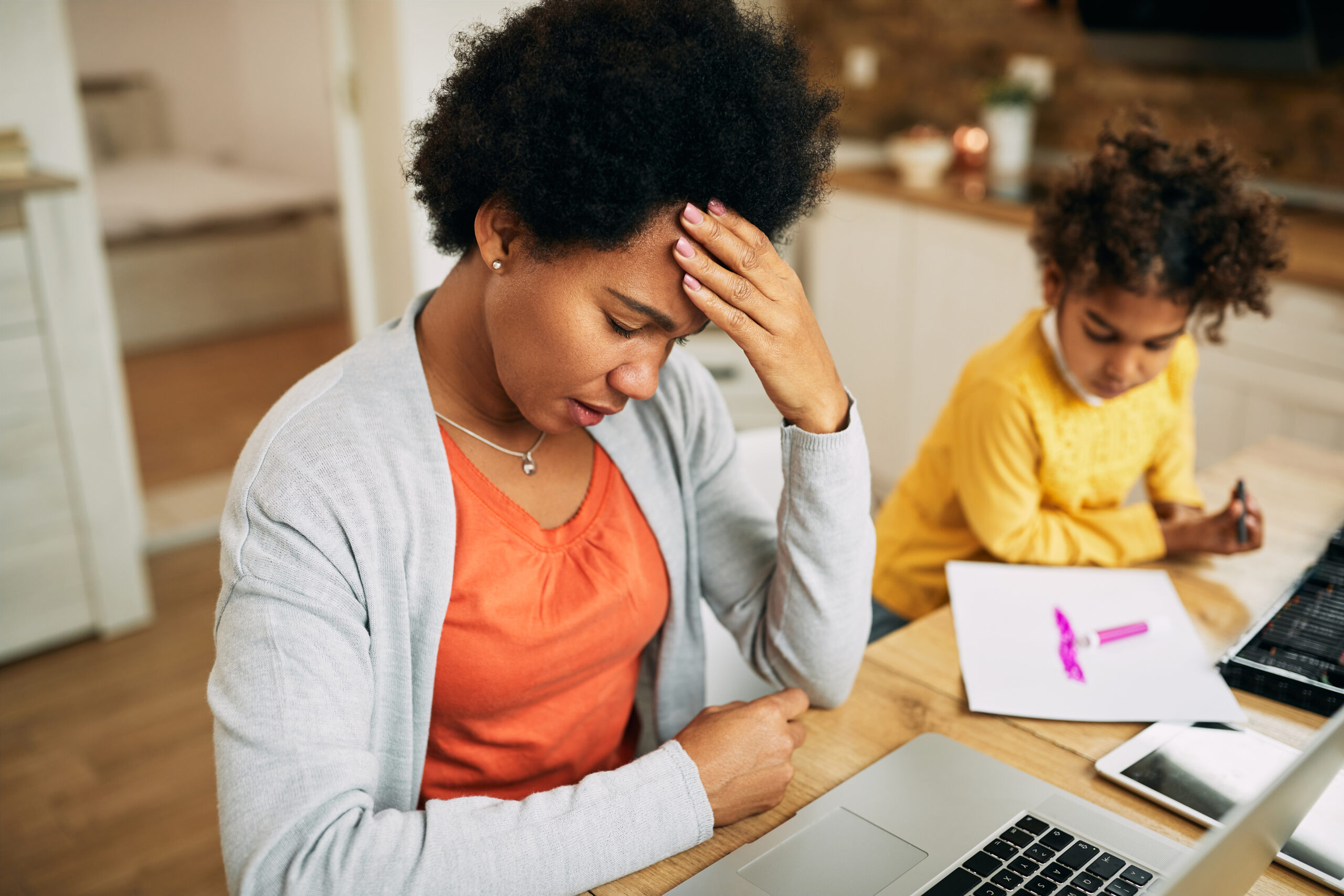 Black single mother having headache while working on laptop at home Acceptance Path Counseling Individual taking a quiet moment to recover from ADHD burnout and mental fatigue