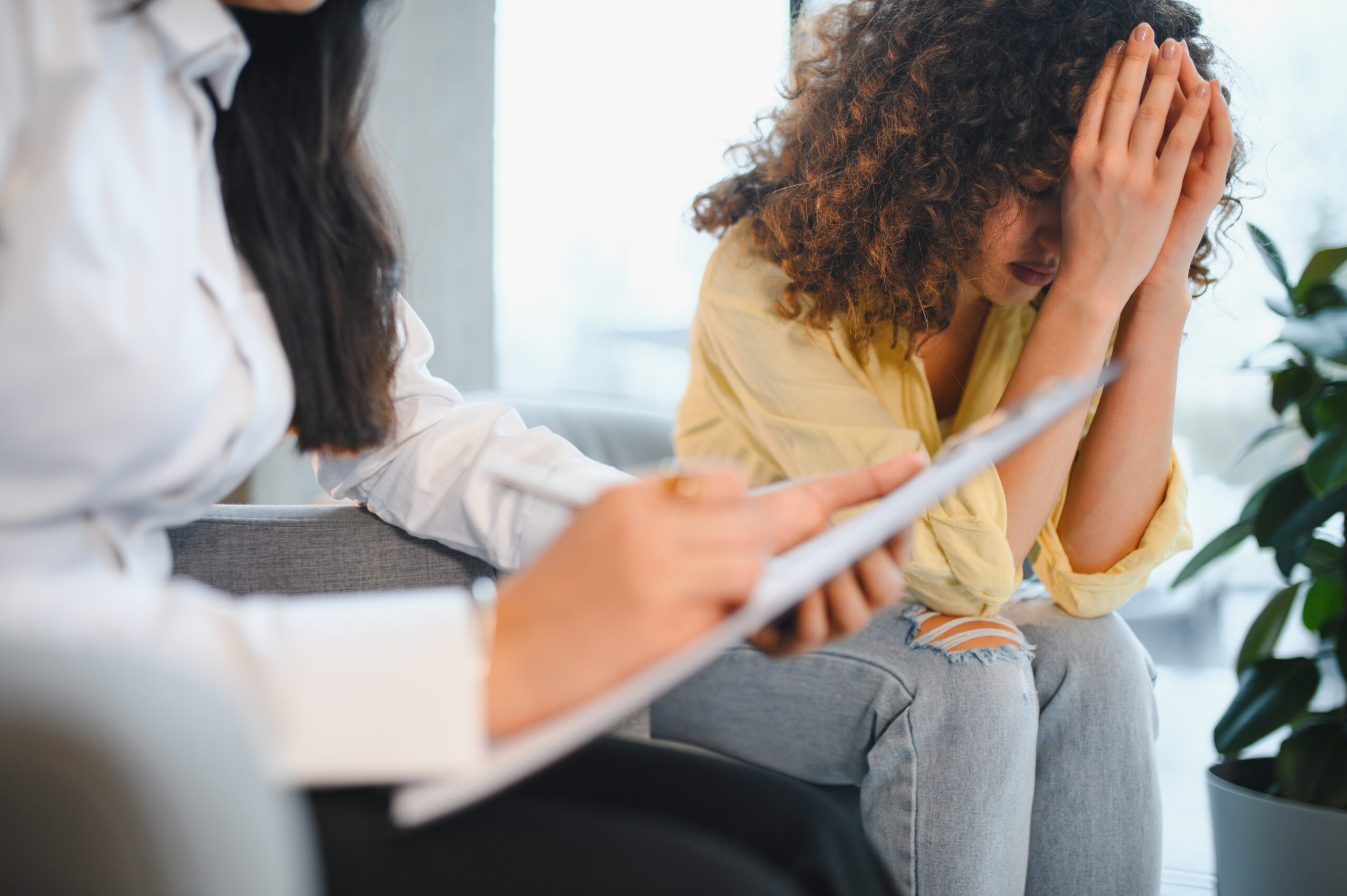 Indian psychologist counseling depressed female patient during therapy session Acceptance Path Counseling Person learning healthy coping strategies for PTSD triggers with therapeutic support