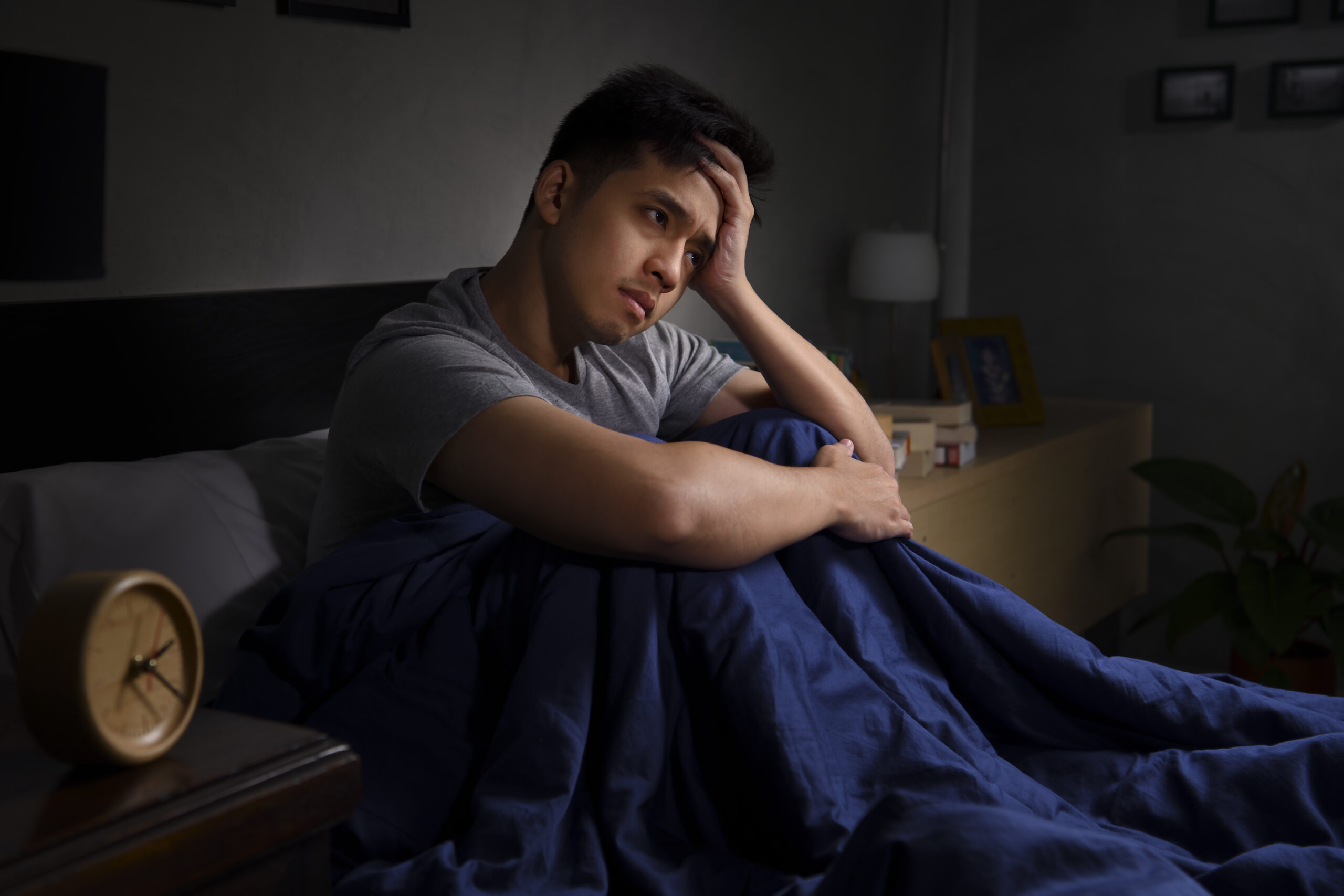 Alarm clock beside a restless person experiencing anxiety at night