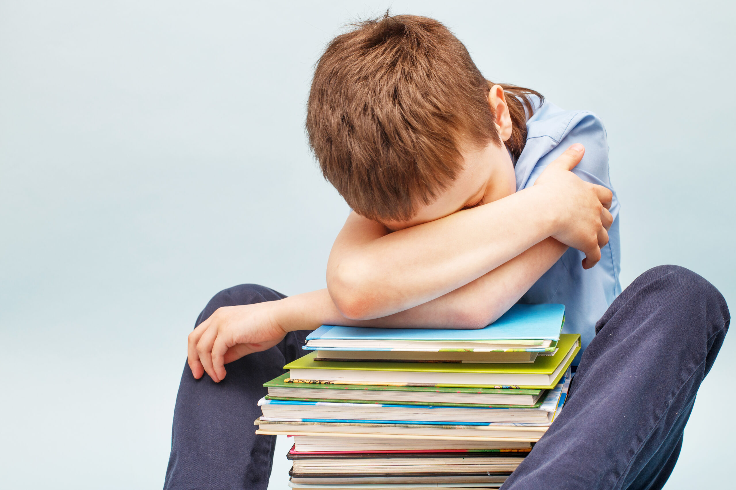Upset schoolboy sitting with pile of school books and covers his face with hands boy sleeping on a stack of textbooks Acceptance Path Counseling Person using a short checklist to move through ADHD task paralysis