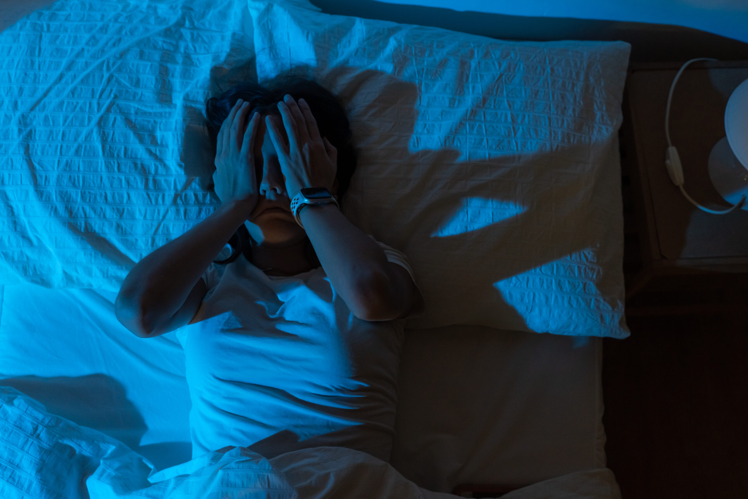 Sleepless person sitting on the edge of a bed after a trauma related nightmare