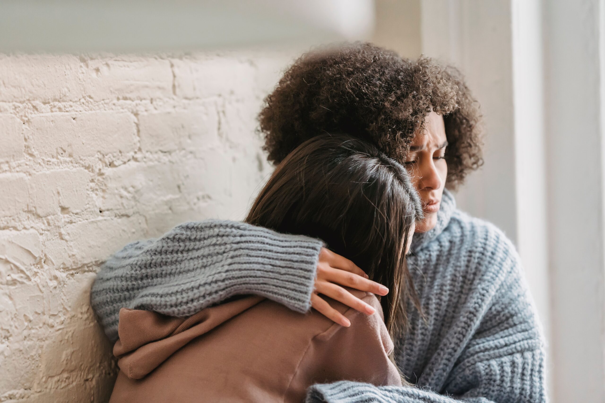 Childhood Trauma in Adults crying on a woman's shoulder.